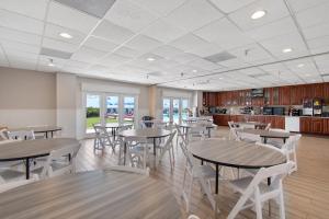 a cafeteria with tables and chairs and a kitchen at Ocean Isle Inn in Ocean Isle Beach