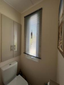 La salle de bains est pourvue de toilettes blanches et d'une fenêtre. dans l'établissement Chalet am See, à Lathum