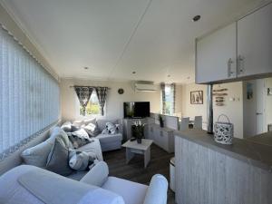 a living room with white furniture and a kitchen at Chalet am See in Lathum