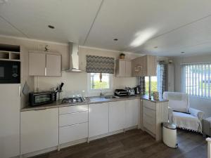 a kitchen with white cabinets and a microwave at Chalet am See in Lathum