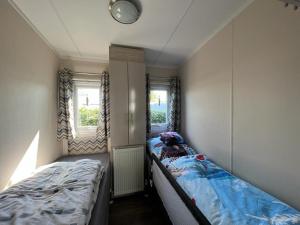 a small bedroom with two beds and two windows at Chalet am See in Lathum