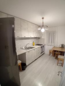 a kitchen with white cabinets and a wooden floor at Apartment Rezidence in Suceava