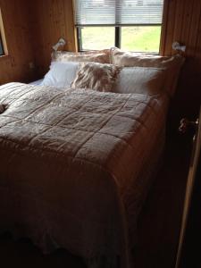 a bed with a blanket and pillows in front of a window at Jaðar Holiday House in Tungufell