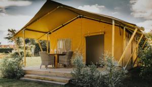 a yellow tent with a table and chairs at Ham Hideaway Boutique Glampsite in Kent