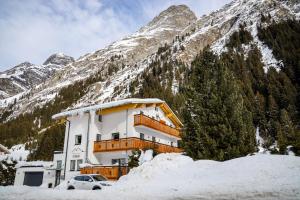 a building in front of a snow covered mountain at Appartements Dobler - s'Darhuam in Sankt Leonhard im Pitztal