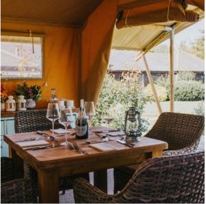 a wooden table with wine glasses and an umbrella at Ham Hideaway Boutique Glampsite in Kent