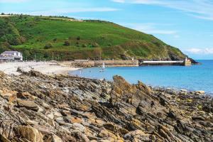 a beach with a train on a hill next to the water at The Apartment, Bridge House in Laxey