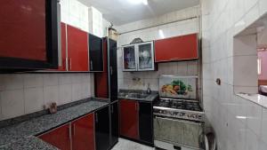 een kleine keuken met rode kasten en een fornuis bij Nice apartment in Caïro