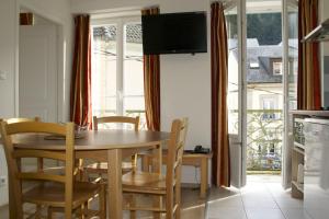 a dining room with a table and chairs and a television at Résidence Maison Blanche in Plombières-les-Bains
