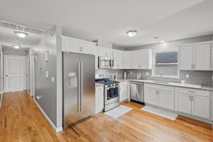 La cuisine est équipée de placards blancs et d'un réfrigérateur en acier inoxydable. dans l'établissement FaithInn - 3 Bed 2 Bath Near EWR/ Downtown/ NYC, à Newark