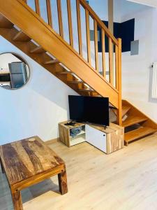 - un salon avec une télévision et un escalier en bois dans l'établissement Appartement spacieux / T2 refais à neuf / proche centre, à Chambéry