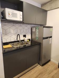 eine Küche mit einer Spüle, einer Mikrowelle und einem Kühlschrank in der Unterkunft Tranquilo Apart en Palermo 2 ambientes in Buenos Aires