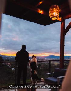Ein Mann, eine Frau und ein Hund mit Blick auf den Sonnenuntergang. in der Unterkunft NidoGredos Cabañas Ecológicas de Diseño in El Tiemblo