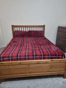 uma cama com um cobertor xadrez e uma moldura de madeira em Excellent stay em Leicester