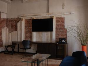 a living room with a television on a brick wall at Grand Hotel in Łódź