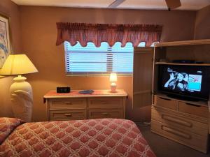 a bedroom with a bed and a television and a window at 107 - 2/2 Poolside in Edgewater +55 photos