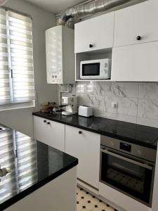 a kitchen with white cabinets and a black counter top at Appartement refait à neuf au pied de paris Paris in Saint-Ouen