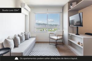 a living room with a white couch and a window at Charlie Connect PUC in Porto Alegre