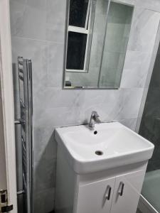 Baño blanco con lavabo y espejo en Home away from home, en Leicester