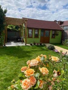 uma casa verde com um monte de rosas no quintal em Charming Private Guest House em Enfield