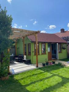 ein grünes Haus mit einer Pergola auf einem Hof in der Unterkunft Charming Private Guest House in Enfield