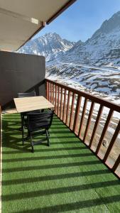 a table and chairs on a balcony with snow covered mountains at Studio la Mongie Tourmalet 2 étoiles in Bagnères-de-Bigorre