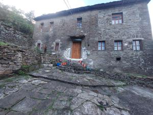 a stone building with a wooden door and stairs in front at guest house in buhal in Përmet