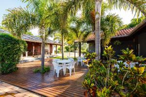 een patio met palmbomen en witte tafels en stoelen bij Hotel Morro De Santo Agostinho in Serra Negra