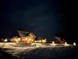 a group of houses in the snow at night at Bieszczadzkie Dworki in Ropienka