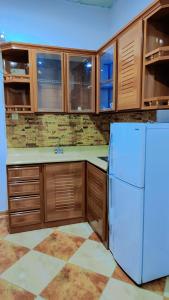 a kitchen with a white refrigerator and wooden cabinets at منتجع الريحانه فله رقم 1 in Taif
