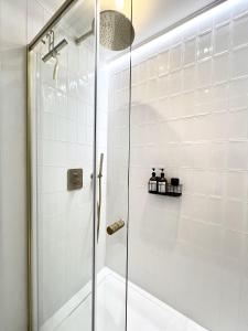 een douche met een glazen deur in de badkamer bij 3 min walk-MEIR Cozy 3-4BR house in Antwerpen