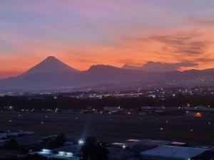 vistas a una montaña al atardecer con una ciudad en Amazing Volcano Views in front of airport en Guatemala