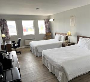 Habitación de hotel con 2 camas y escritorio en Florenceville Inn, Restaurant & Pool, en Florenceville