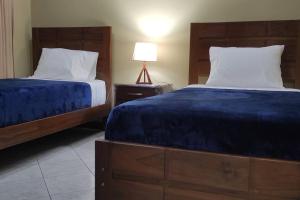 a bedroom with two beds with blue sheets and a lamp at Departamento frente a Plaza Sucre, vista panorámica, 6 personas, 2 habitaciones, ascensor, garaje extra in Tarija