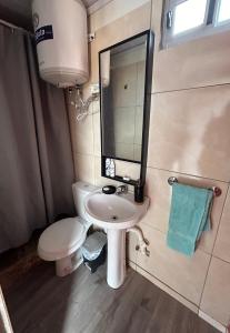 een badkamer met een wastafel, een toilet en een spiegel bij Casa Conteiner en campo con playa privada. max 6 personas in Jaureguiberry