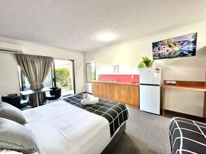 Mackay Resort Motel في ماكاي: غرفه فندقيه بسرير وثلاجه