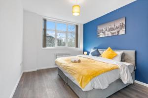 ein Schlafzimmer mit blauen Wänden und ein Bett mit einer gelben Decke in der Unterkunft Leicester Aparthotels - Churchgate in Leicester