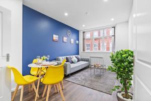ein Wohnzimmer mit einem Sofa, einem Tisch und gelben Stühlen in der Unterkunft Leicester Aparthotels - Churchgate in Leicester