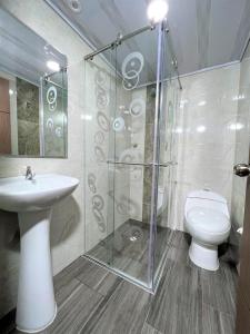 uma casa de banho com um WC e uma cabina de duche em vidro. em HOTEL ANGELES J&A em Tunja