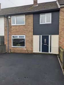 a brick house with a blue door and a parking lot at Moorside Terrace in Guisborough +11 photos
