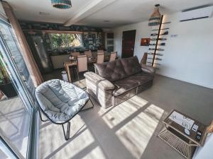 a living room with a couch and a chair at Villa Verde Bangalô - Garopaba - SC in Garopaba