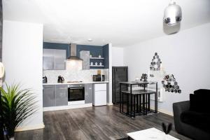 a living room with a kitchen and a table at Stylish two-bedroom Salford Quays apartment in Manchester