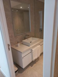 La salle de bains est pourvue d'un lavabo blanc et d'un miroir. dans l'établissement Trump Tower, à Punta del Este