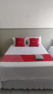 a large white bed with red pillows on it at HOTEL CYSNE in Sobral
