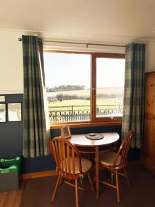 a dining room with a table and chairs and a window at Orchard House Lodges by Ecohuman in Haddington