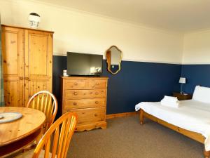 a bedroom with a bed and a table and a tv at Orchard House Lodges by Ecohuman in Haddington