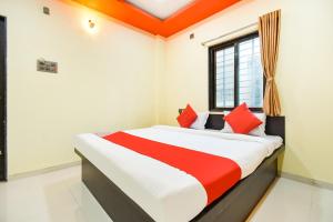 um quarto com uma cama grande e almofadas vermelhas em OYO Flagship Hotel Manish Inn em Aurangabad