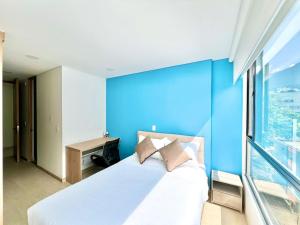 a bedroom with a blue wall and a bed with pillows at Apartamentos Weeki en Chapinero in Bogotá
