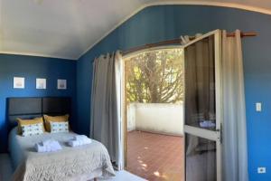 - une chambre bleue avec un lit et une porte coulissante en verre dans l'établissement Chalet del Sol, à Luján de Cuyo