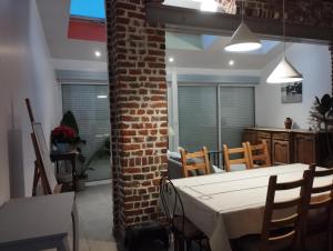 uma sala de jantar com uma parede de tijolos e uma mesa e cadeiras em Charmante maison proche de toutes commodités em Croix